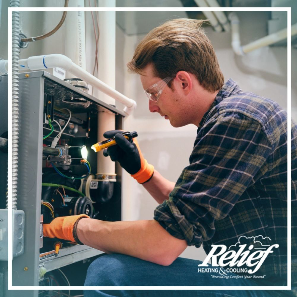 An HVAC technician inspecting the internal components of a furnace at a client's home for Relief Heating and Cooling, LLC in Greensboro, NC.