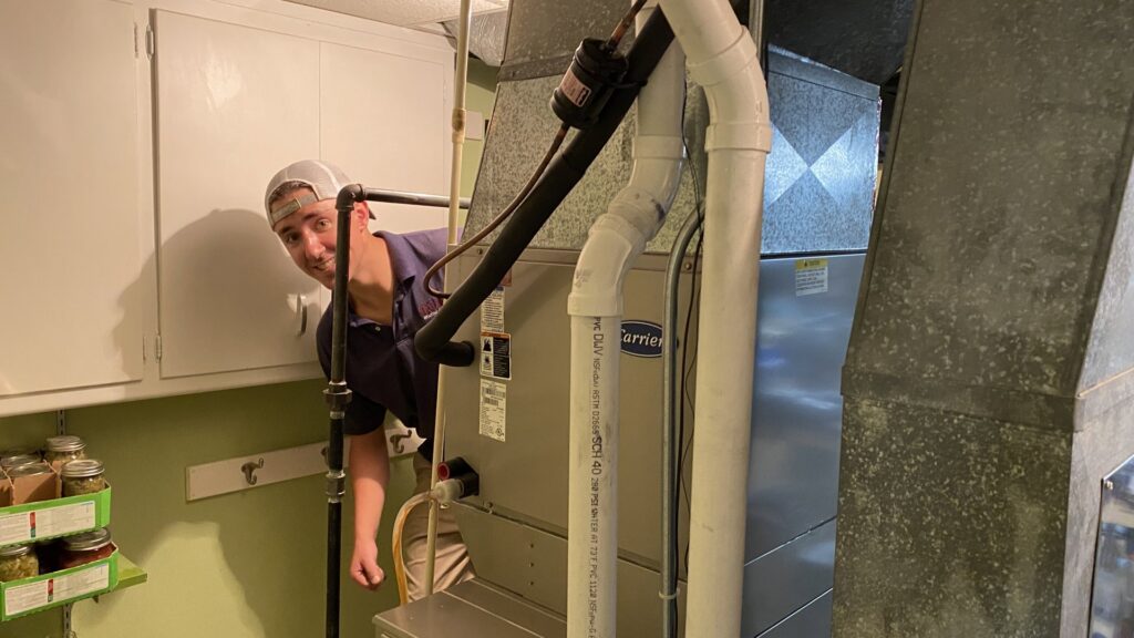 An HVAC technician inspecting a furnace unit for Tom's Heating Service in Waukesha, WI.