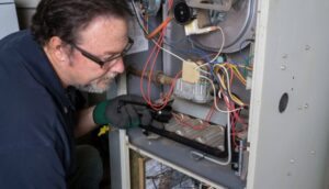 An HVAC technician inspecting the internal components of a furnace or air handler for Viking Heating and Air Conditioning, LLC in Chandler, AZ