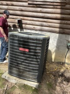 An HVAC technician inspecting a Goodman outdoor air conditioning unit for Know A Guy Heating & Air Conditioning in Kernersville, NC.