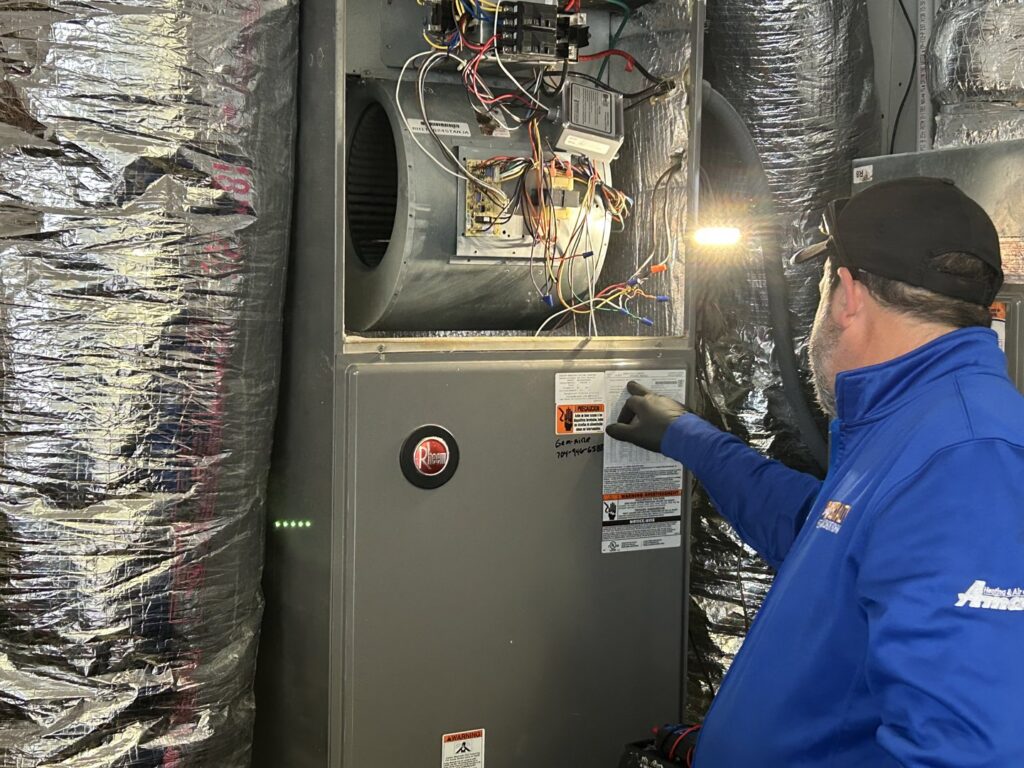 An Air Specialty Heating & Air Conditioning technician inspecting an indoor HVAC furnace unit in Norfolk, VA.