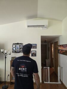 A Best Heat & Air technician inspecting a wall-mounted mini-split indoor unit in Tacoma, WA.