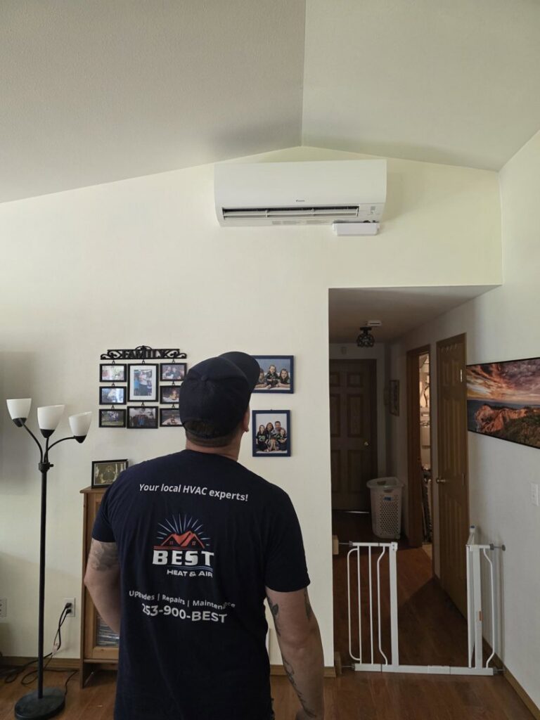 A Best Heat & Air technician inspecting a wall-mounted mini-split indoor unit in Tacoma, WA.