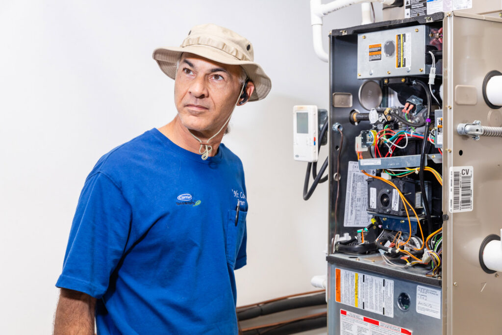An HVAC technician from Mr. Cool HVAC inspecting an open furnace or air handler unit during a service call in Cypress, TX.