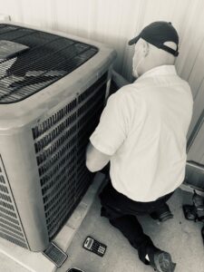 An HVAC technician from McCarthy's One Hour Heating & Air Conditioning inspecting an outdoor AC unit in Omaha, NE.