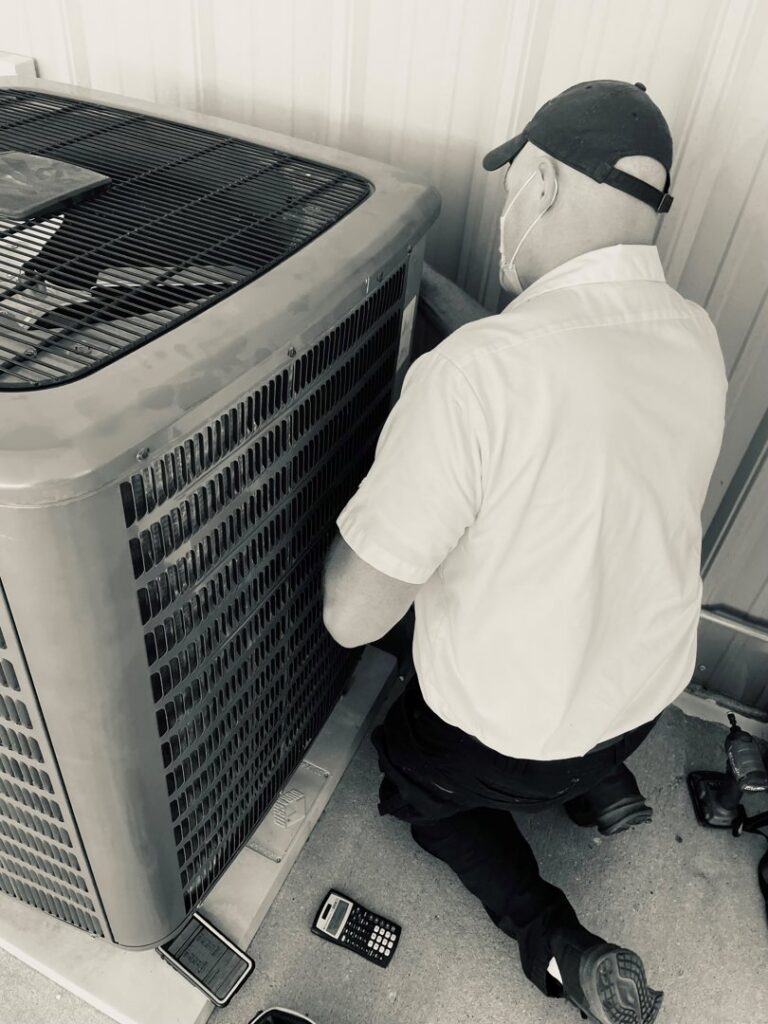 An HVAC technician from McCarthy's One Hour Heating & Air Conditioning inspecting an outdoor AC unit in Omaha, NE.