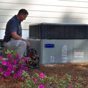 An HVAC technician inspecting an outdoor heating and air conditioning unit for Foust Heating & Air Conditioning in Fayetteville, NC.
