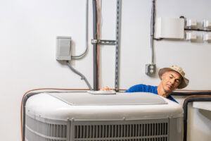 An HVAC technician from Mr. Cool HVAC inspecting the top of a large outdoor air conditioning unit in Cypress, TX.