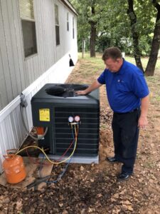 An HVAC technician from My Texas Home Services inspecting an outdoor air conditioning unit in Dallas, TX.