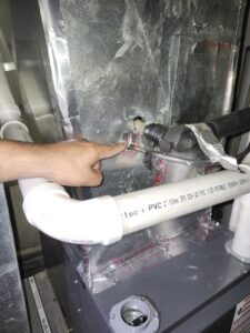An HVAC technician inspecting a refrigerant line connection on an indoor unit by Giant HVAC in Chicago, IL
