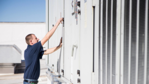An HVAC technician inspecting a large commercial rooftop unit for Hyland Filter Service in Owensboro, KY.
