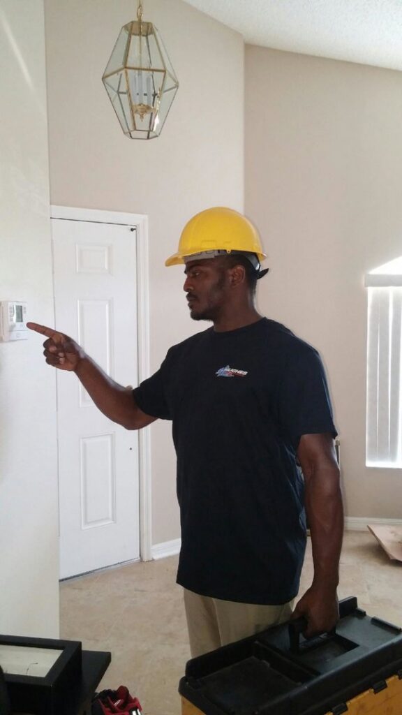 An HVAC technician from Hughes Air Heating & Cooling inspecting a thermostat during a service call in Mesa, AZ.