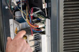 An HVAC technician from DFH Company Heating and Air Conditioning inspecting wiring inside an HVAC unit in Louisville, KY