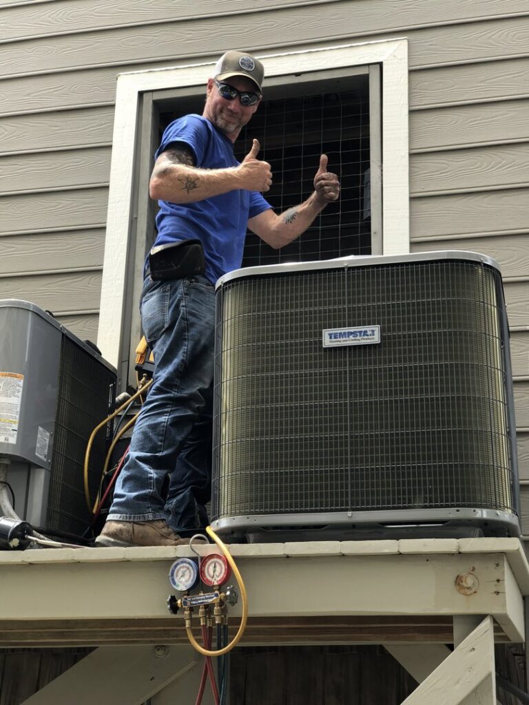 An HVAC technician giving a thumbs up next to a newly installed outdoor AC unit in Sumter, SC by Advance Heating & Air, Inc.