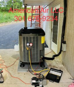 An HVAC technician from American Air LLC installing an AC unit, connected to gauges and a vacuum pump, in Moncks Corner, SC