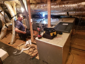 An HVAC technician installing an air handler unit in an attic at Comfort Zone A/C & Heating, LLC in Kenner, LA.