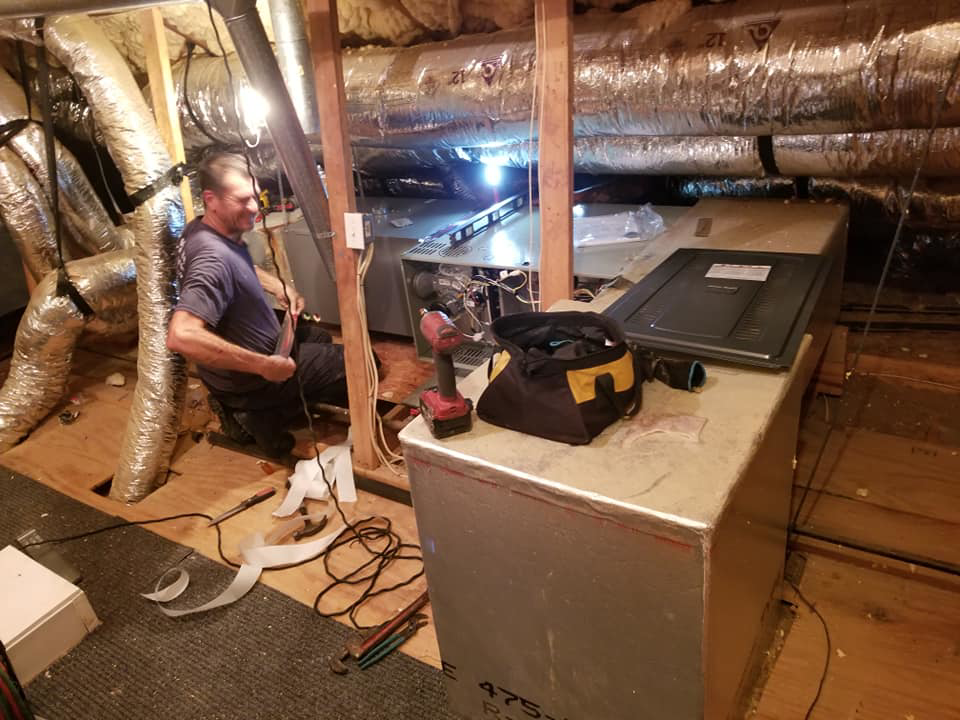 An HVAC technician installing an air handler unit in an attic at Comfort Zone A/C & Heating, LLC in Kenner, LA.