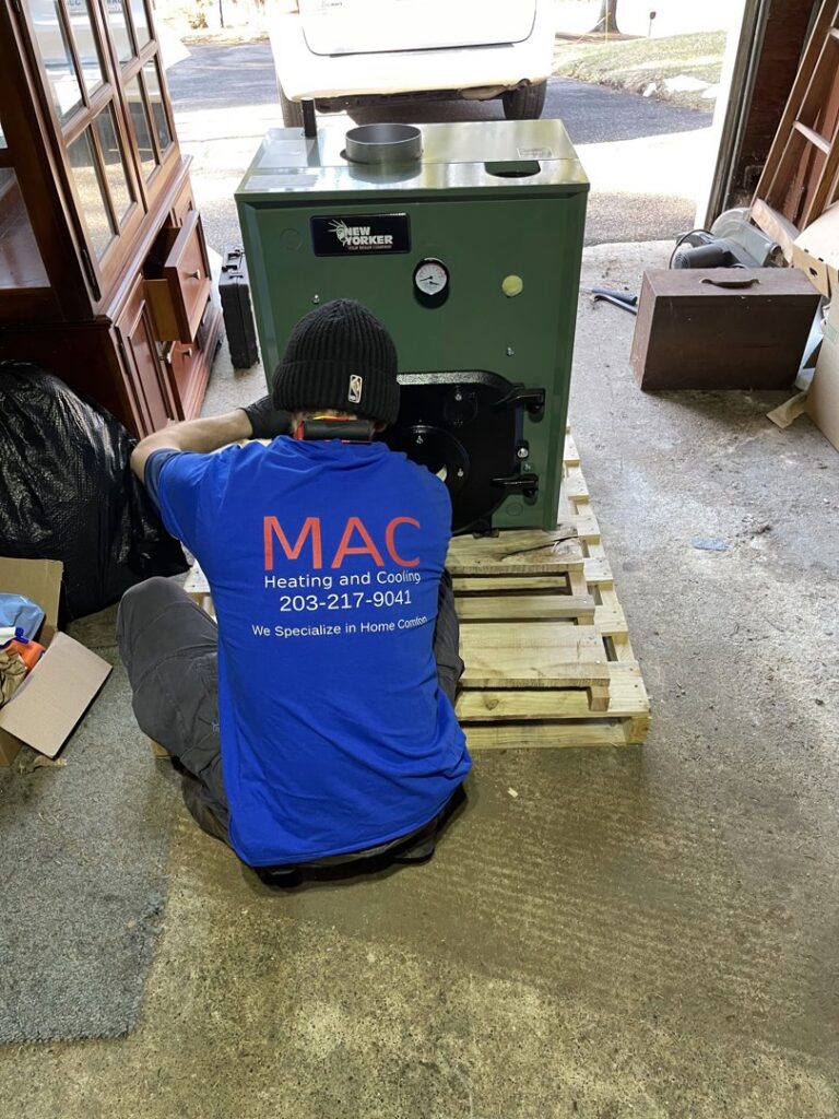 An HVAC technician from MAC Heating and Cooling LLC installing a new boiler unit in Waterbury, CT.