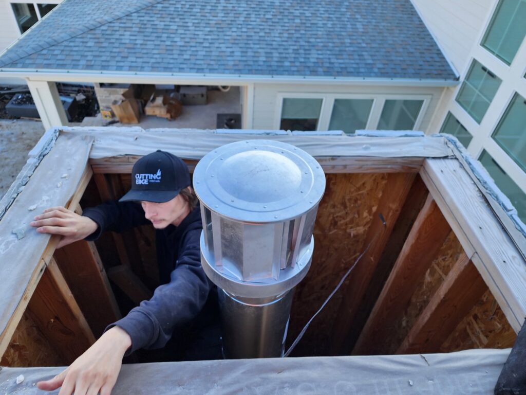 An HVAC technician installing a chimney flue or vent on a roof for Cutting Edge HVAC LLC in Orem, UT.