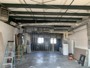 An HVAC technician installing ductwork and a heating unit for Lbz Construction in Charleston, SC