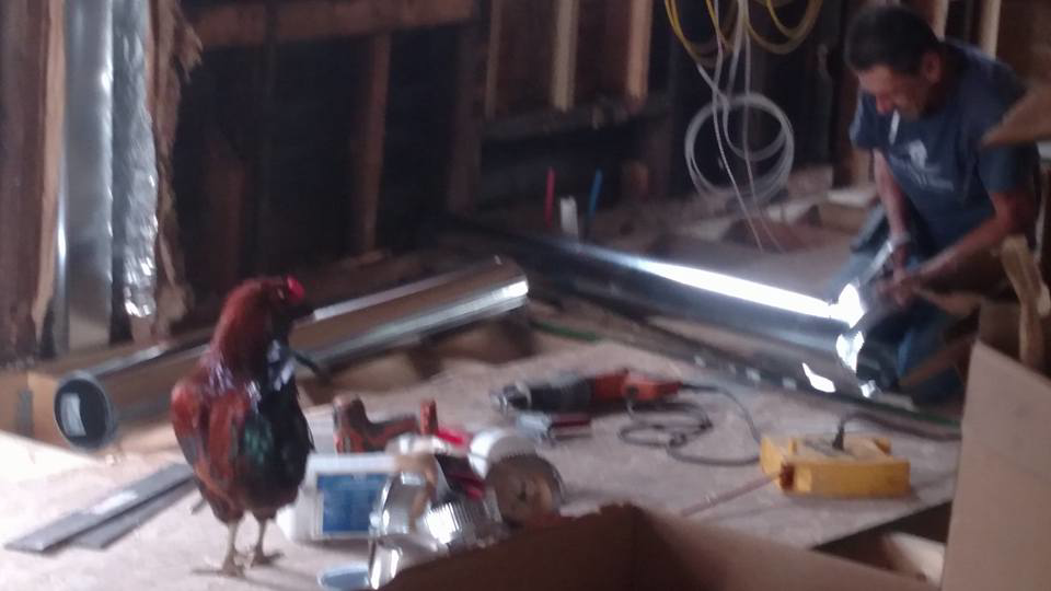 An HVAC technician installing ductwork at a job site for Collins Cooling and Heating in Cleveland, OH.