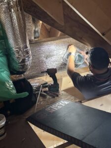 An HVAC technician installing ductwork in an attic for Comfort Systems and Solutions in Coventry, RI