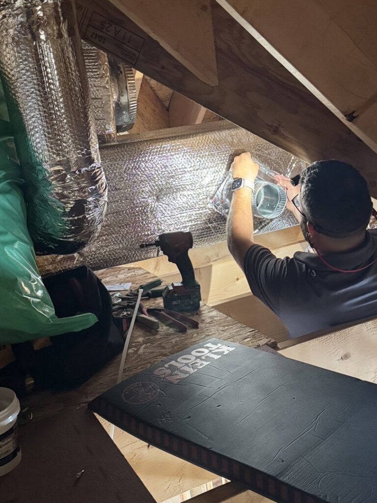 An HVAC technician installing ductwork in an attic for Comfort Systems and Solutions in Coventry, RI