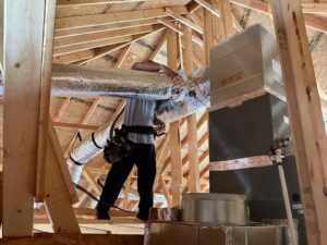 An HVAC technician installing insulated ductwork in an attic for Diversified Services NA in Rogers, AR.