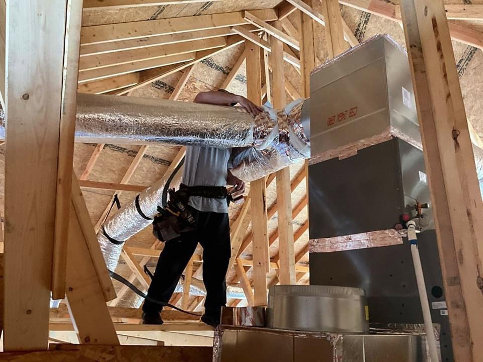 An HVAC technician installing insulated ductwork in an attic for Diversified Services NA in Rogers, AR.