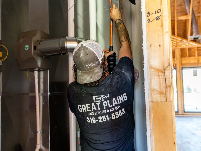 An HVAC technician from Great Plains Heating & Air installing ductwork in a new construction home in Goddard, KS.