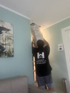 A Hendrix Heating & Air technician installing new ductwork in a ceiling opening in Newport News, VA.