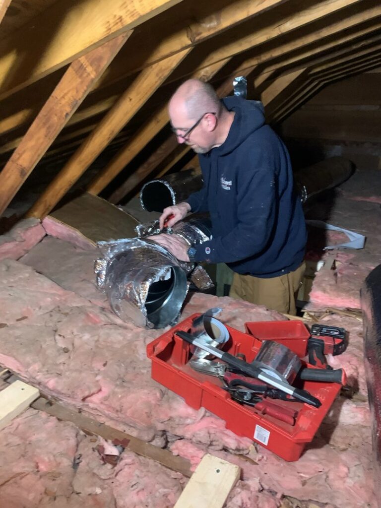An HVAC technician installing or repairing ductwork in an attic for Miller's Home Comfort-Chesapeake in Chesapeake, VA.