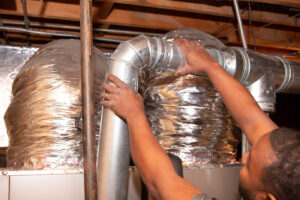 An HVAC technician from Nashville Solutions installing or repairing ductwork in a home in Nashville, TN