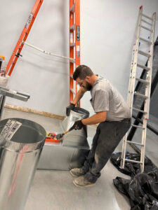 An HVAC technician installing or repairing ductwork for One Hour Heating & Air Conditioning of West Valley in Phoenix, AZ