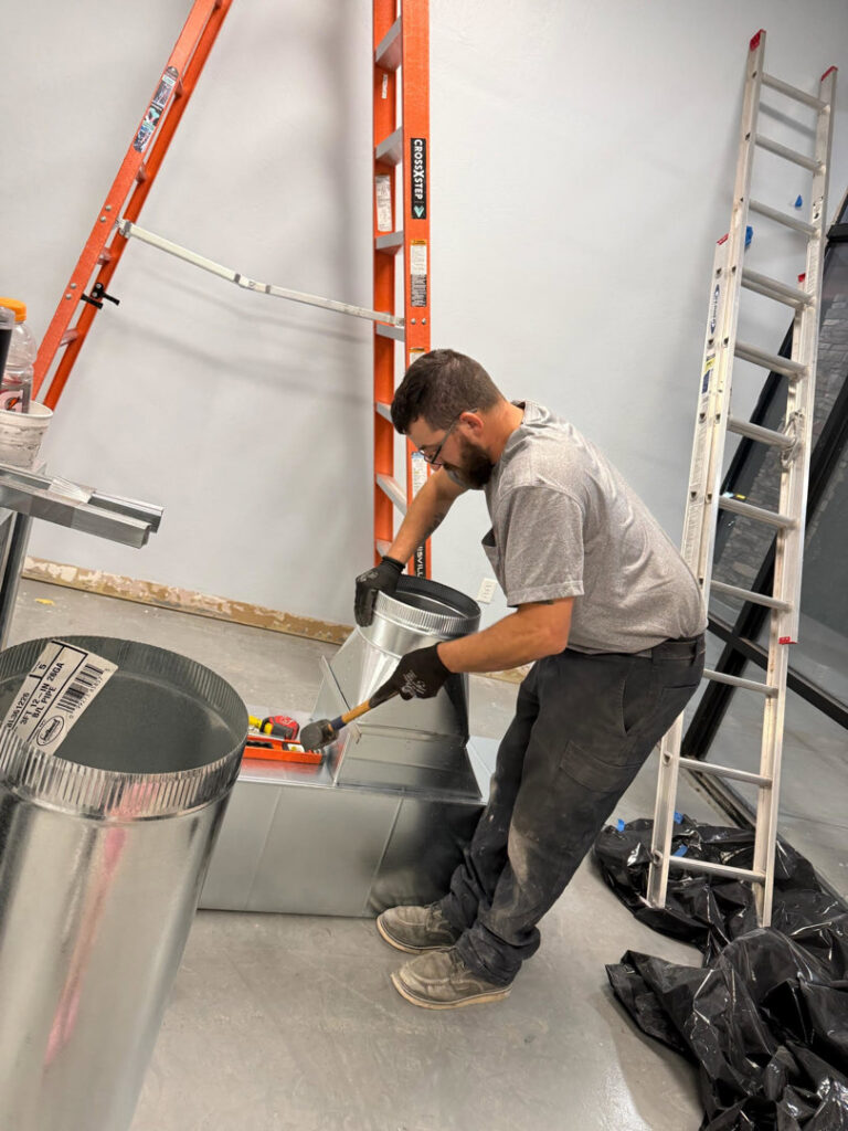 An HVAC technician installing or repairing ductwork for One Hour Heating & Air Conditioning of West Valley in Phoenix, AZ