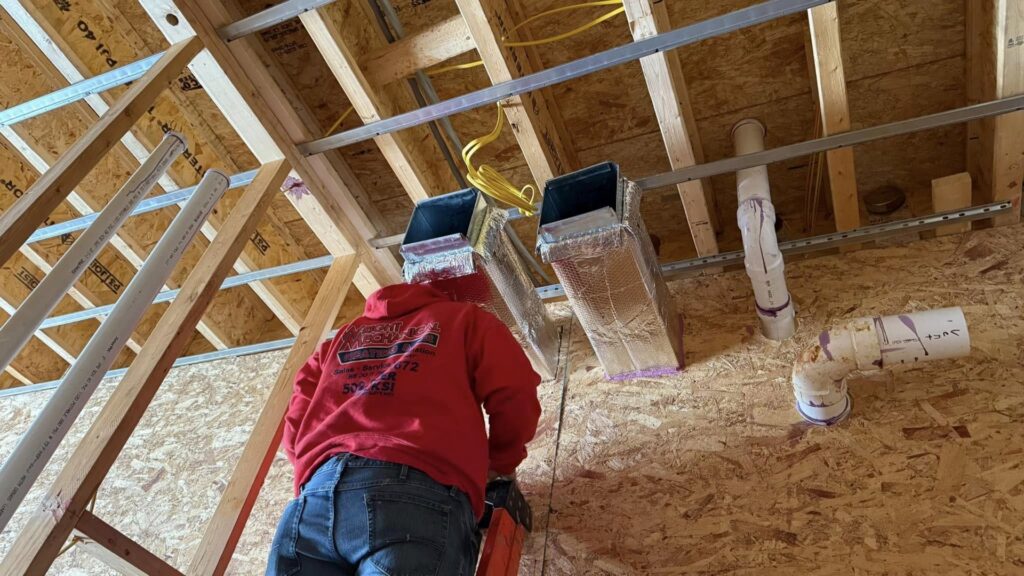 An HVAC technician installing ductwork in a new construction by Wright Heating and Air in Louisville, KY.