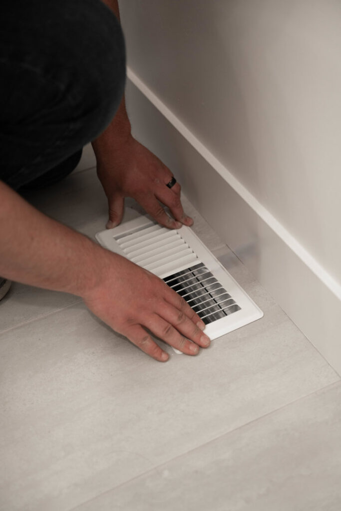An HVAC technician from CSA HVAC Services installing a floor air vent in Orem, UT.