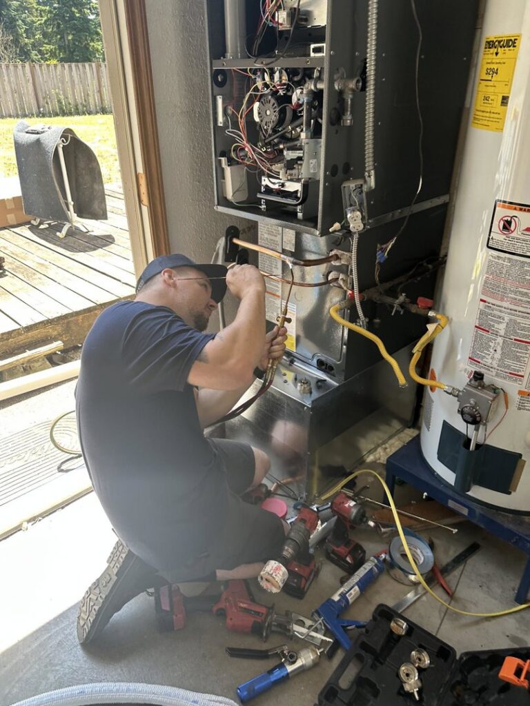 A Best Heat & Air technician installing or repairing an indoor furnace unit in Tacoma, WA.