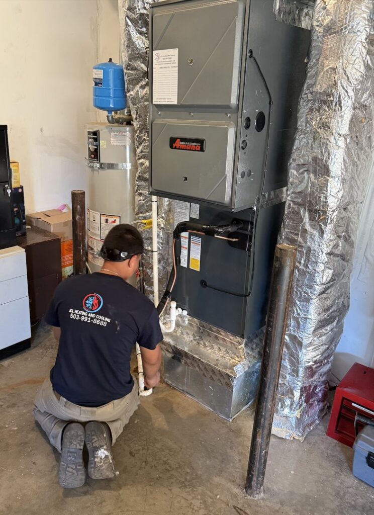An HVAC technician from JCL Heating and Cooling LLC installing an indoor furnace unit in Gresham, OR.