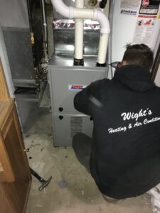 An HVAC technician from Wight's Heating & Air Conditioning installing a new furnace unit in Rockford, IL
