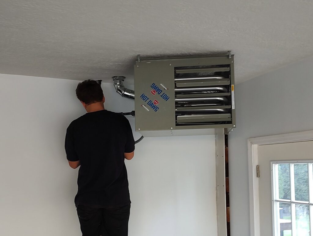 An HVAC technician from Wyles Heating & Air Conditioning Inc. installing a ceiling-mounted garage heater in North Canton, OH.