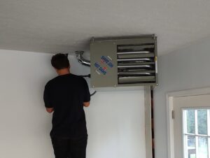 An HVAC technician from Wyles Heating & Air Conditioning Inc. installing a ceiling-mounted garage heater in North Canton, OH.