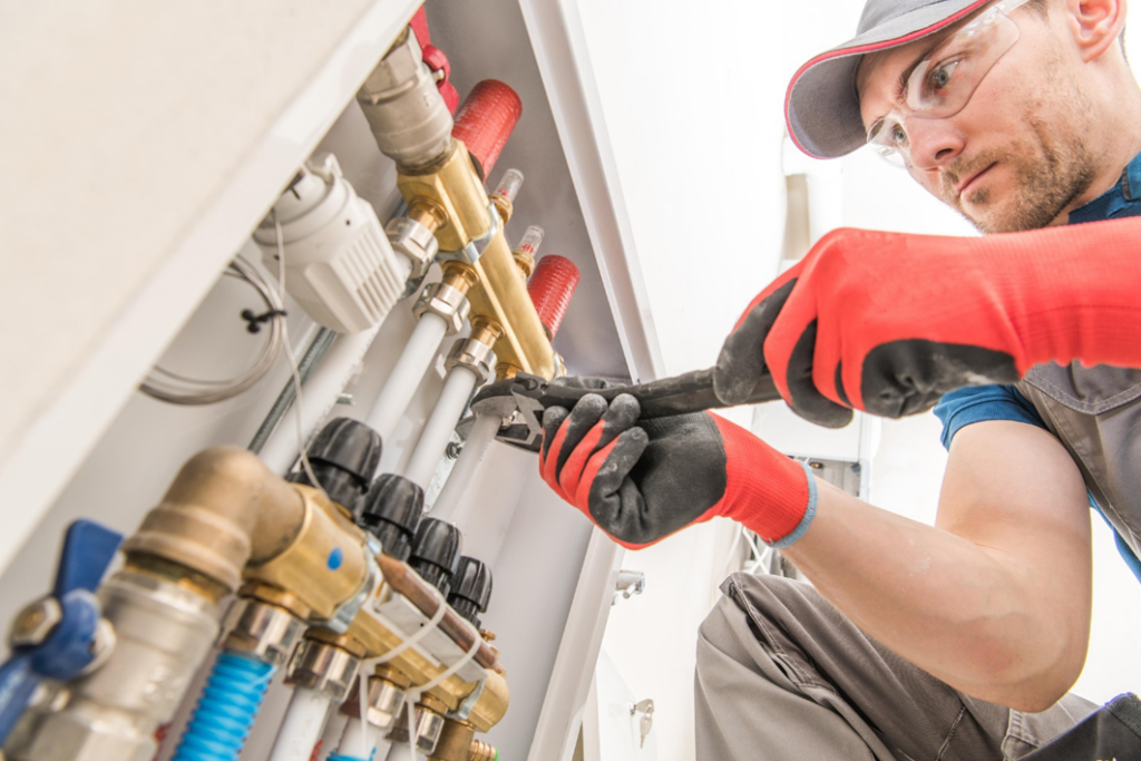 An HVAC technician installing a heating manifold system at Derry Plumbing & Heating in Derry, NH.