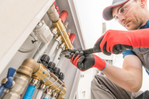 An HVAC technician installing a heating manifold system at Derry Plumbing & Heating in Derry, NH.