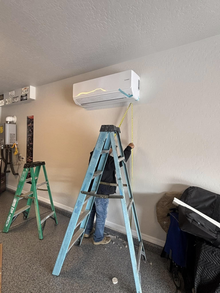 An HVAC technician installing a mini-split AC unit at a client's property for Buddy's Refrigeration LLC in Mesquite, NV.