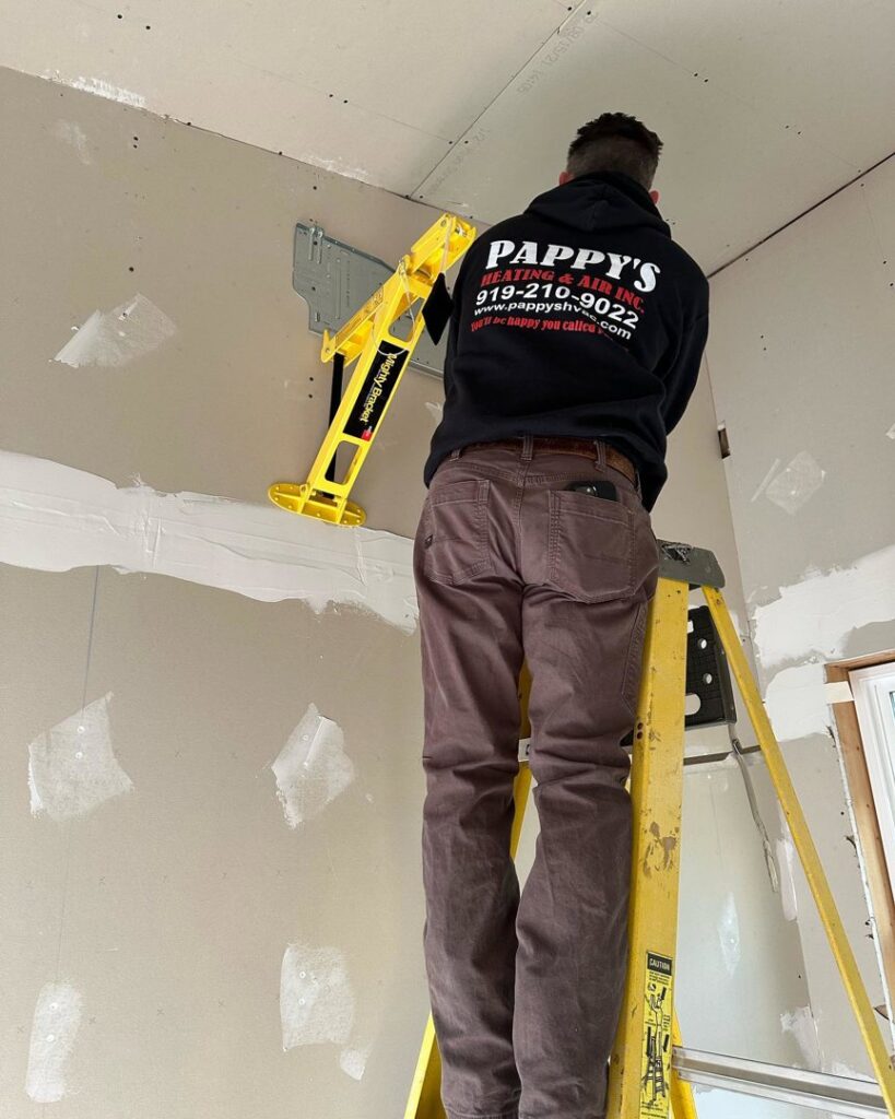 An HVAC technician from Pappy's Heating & Air INC installing a mini-split indoor unit bracket in Clayton, NC.