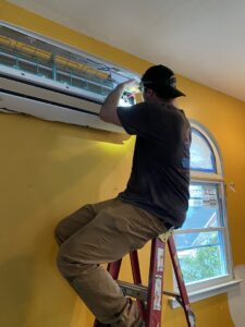 An HVAC technician from Brand Air Heating and Cooling LLC installing an indoor mini-split unit in Wilmington, NC.