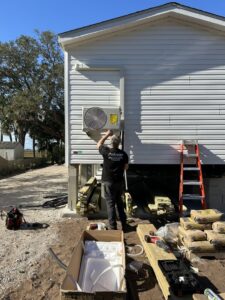 An HVAC technician installing an outdoor mini-split air conditioning unit on a residential home by Whitleys Heating and Air in Jacksonville, FL.