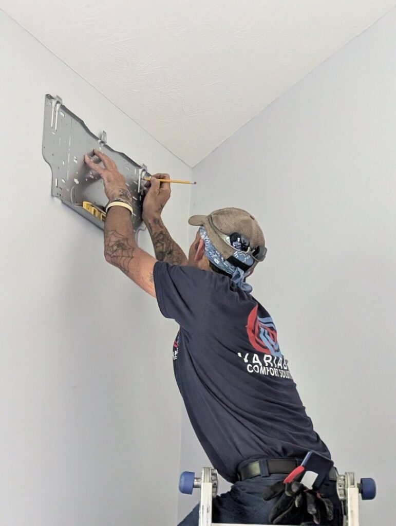 An HVAC technician installing an indoor mini-split unit on a wall for Variable Comfort Solutions in Huntington, WV.