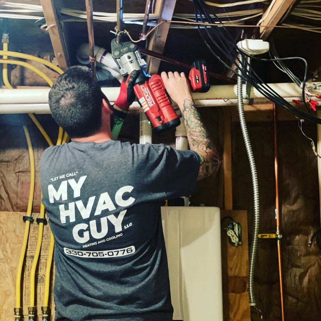 An HVAC technician from My HVAC Guy installing pipes for a heating or water system in North Canton, OH.